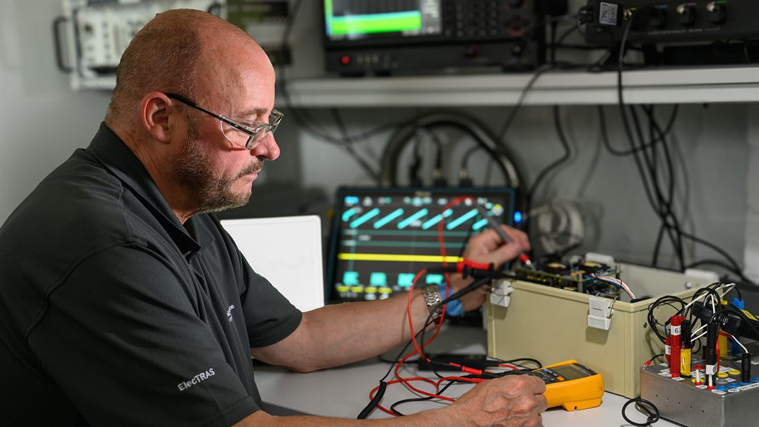 An elecTRAS engineer probing test electronics with an oscilloscope